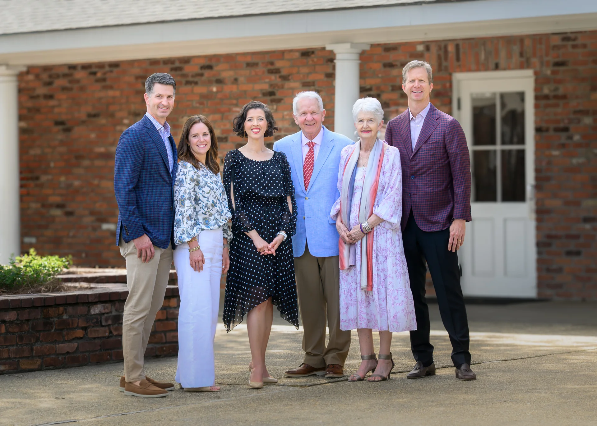 Lisette poses with members of the Spaht and Dodson families outside a brick Episcopal School building.
